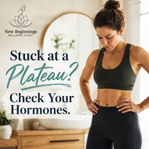 A fit woman in workout clothes looking frustrated while checking her progress in a bathroom mirror at New Beginnings Wellness Clinic. Text overlay reads "Stuck at a Plateau? Check Your Hormones."